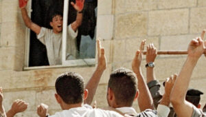 Aziz Salha, einer der Teilnehmer an der Ermordung zweier Reservisten der israelischen Streitkräfte im Jahr 2000 in Ramallah, hält seine blutbefleckten Hände in der Polizeistation der Palästinensischen Autonomiebehörde in al-Bireh hoch. Foto: Palestinian Media Watch.