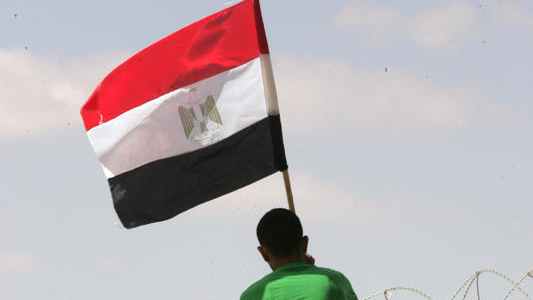 Ein palästinensischer Mann hisst eine ägyptische Flagge an der Grenze zwischen dem Sinai und Gaza. Foto von Abed Rahim Khatib/Flash90
