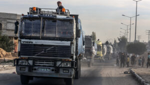 Bewaffnete und maskierte Palästinenser der Hamas sichern Lastwagen mit humanitären Hilfsgütern, die über den israelischen Grenzübergang Kerem Shalom auf der Salah al-Din-Straße östlich von Khan Yunis im südlichen Gazastreifen einfahren, 19. Januar 2025. Foto von Abed Rahim Khatib/Flash90