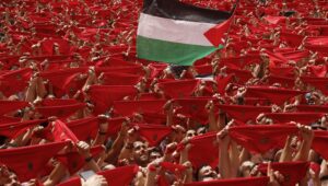 Eine Person schwenkt eine palästinensische Flagge, während die Menschen auf den Start der Chupinazo-Rakete warten, die den Beginn der San Fermin-Festlichkeiten in Pamplona, Spanien, am 6. Juli 2025 markiert. EPA/Villar Lopez