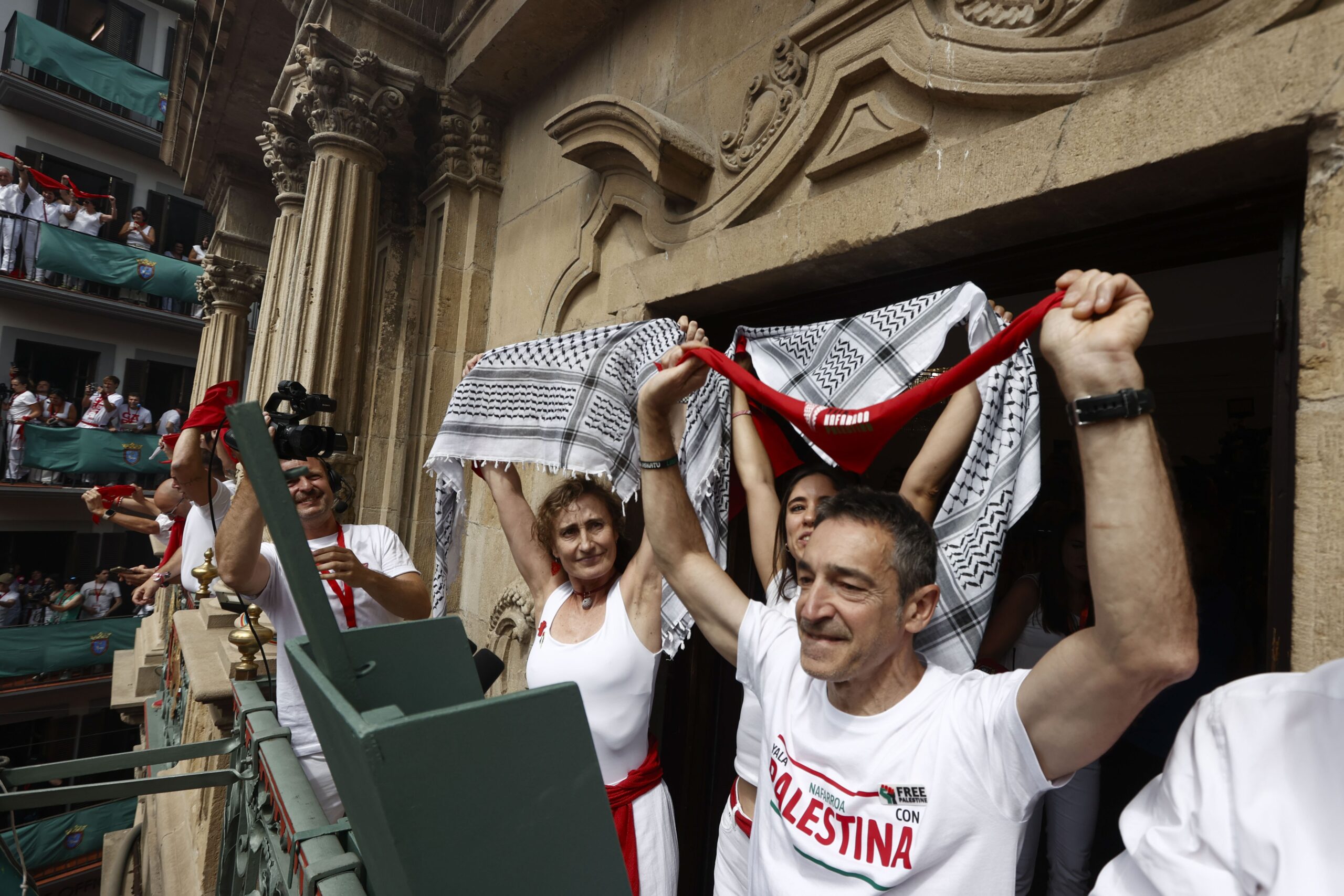 Vertreter von Yala Nafarroa per Palestine Dyna Kharrat (Mitte), Lidon Soriano (links) und Eduardo Ibero (rechts) posieren auf dem Balkon des Rathauses kurz vor dem Abschuss des Chupinazo-Feuerwerks, das am 6. Juli 2025 in Pamplona, Spanien, offiziell die San-Fermin-Feierlichkeiten eröffnet. EPA/JESUS DIGES