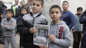 Familienangehörige von Ibrahim Akkari halten sein Bild als Märtyrer in ihrem Haus im Flüchtlingslager Shuafat hoch, nachdem er von der israelischen Polizei erschossen wurde, nachdem er in Jerusalem einen Autoangriff verübt hatte. Der Mann aus Shuafat fuhr mit seinem Auto in eine Menschenmenge, die an der Stadtbahnhaltestelle Shimon ha Tzadik in Jerusalem wartete, und verletzte dabei mindestens acht Menschen und tötete mindestens einen Passanten. Der Fahrer wurde in der Nähe des Tatorts erschossen. 5. November 2014. Foto: Sliman Khader/FLASH90
