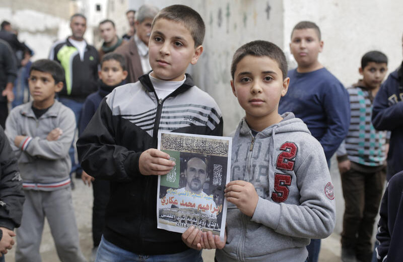 Familienangehörige von Ibrahim Akkari halten sein Bild als Märtyrer in ihrem Haus im Flüchtlingslager Shuafat hoch, nachdem er von der israelischen Polizei erschossen wurde, nachdem er in Jerusalem einen Autoangriff verübt hatte. Der Mann aus Shuafat fuhr mit seinem Auto in eine Menschenmenge, die an der Stadtbahnhaltestelle Shimon ha Tzadik in Jerusalem wartete, und verletzte dabei mindestens acht Menschen und tötete mindestens einen Passanten. Der Fahrer wurde in der Nähe des Tatorts erschossen. 5. November 2014. Foto: Sliman Khader/FLASH90