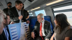 Der israelische Ministerpräsident Benjamin Netanjahu, Verkehrsministerin Miri Regev und weitere Amtsträger betrachten während einer Fahrt auf der neuen Strecke am 19. Mai 2026 eine Karte der Ostbahn der Israelischen Eisenbahn. Foto: Ma’ayan Toaf/GPO.