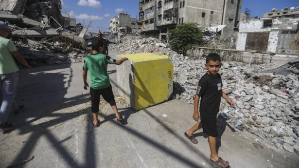 Palästinenser gehen am 27. Juli 2026 im Stadtteil Tufah in Gaza-Stadt an einem gelben Betonblock vorbei, der die unter israelischer Militärkontrolle stehende „gelbe Zone“ markiert. Foto: Ali Hassan/Flash90